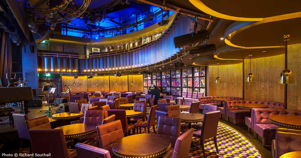 The Matcham Room at the Hippodrome Casino: a small performance room with a stage, booths and warm lighting.